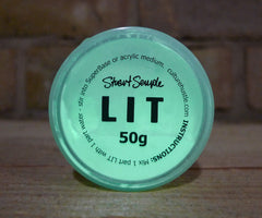 LIT glow pigment powder in a 50g container with a turquoise lid and black text on a wooden surface.