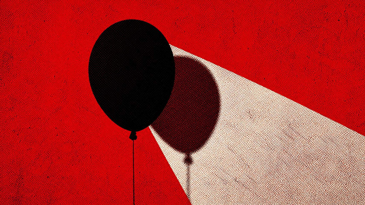 A black balloon on a red wall, its shadow thrown across a beam of light